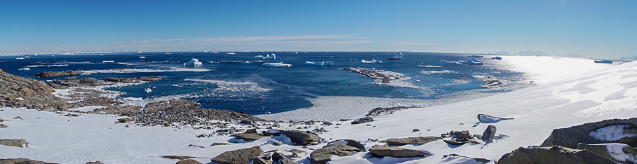 Panorama in Antarctica with crystal blue water surrounded by ice covered mountains