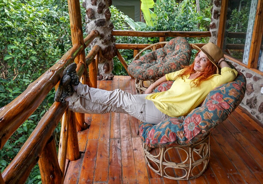 Redhead Woman in yellow shirt and khaki pants lounging on balcony in Uganda. What to Pack for African Safari