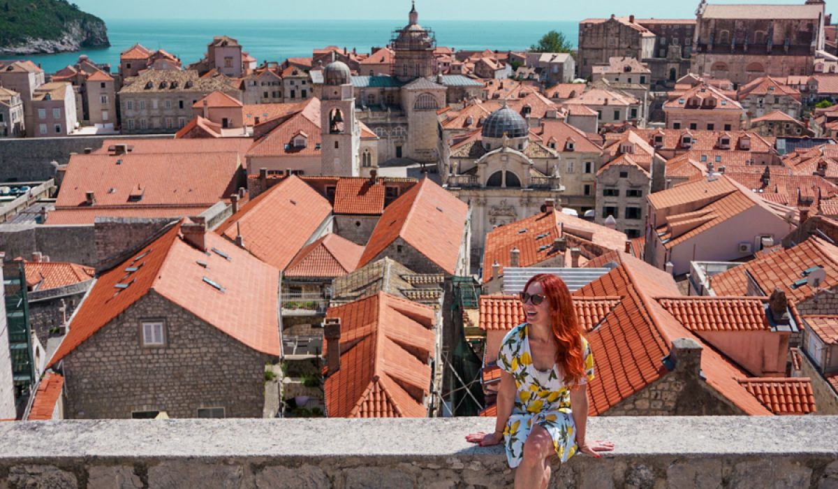 Girl sitting on wall with Dubrovnik city behind her