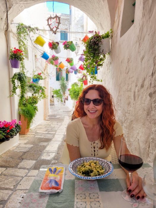 Girl eating at restaurant in scenic alley in Ostuni Italy