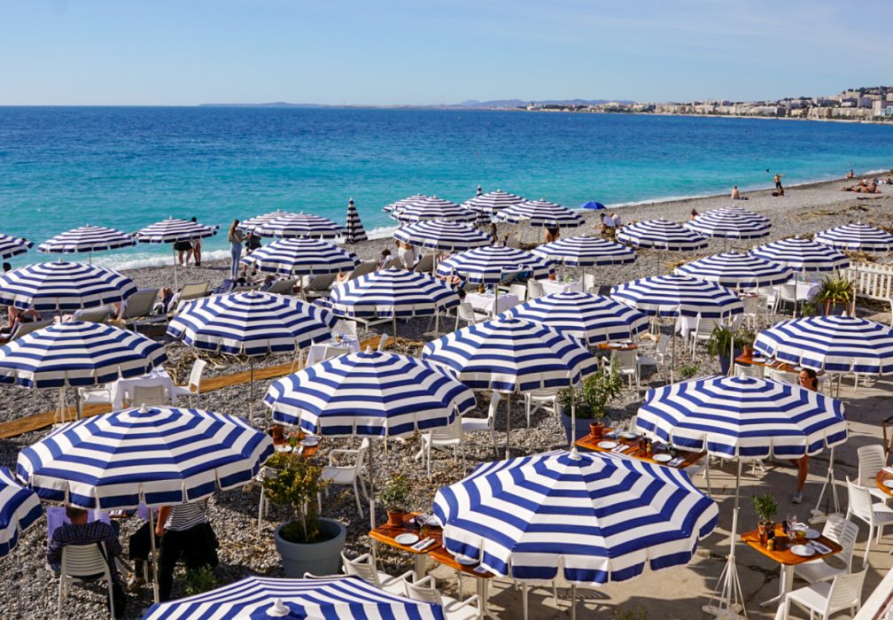 Blue and white umbrellas along the blue sea in Nice, France